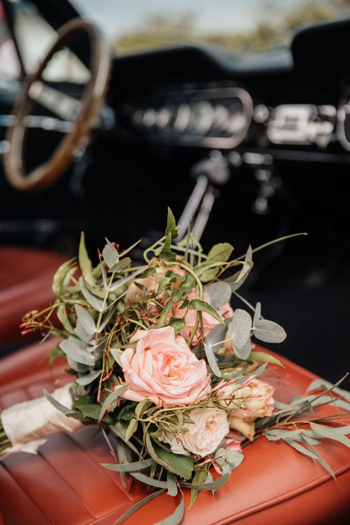 trouwauto en trouwboeket op de stoel
